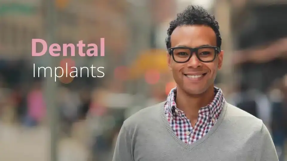 Smiling man with glasses wearing checkered shirt in New York dental office.